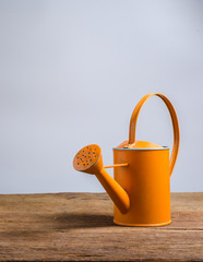 Retro Orange watering can on wooden table © bookzaa