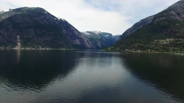 Flying low above dark waters of Hardanger fjord in Norway with scenic views of cliffs surrounding it. Aerial 4k Ultra HD.