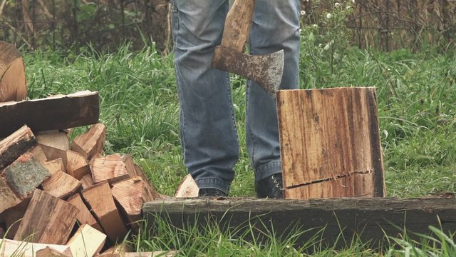 Lumberjack cutting firewood with axe in backyard