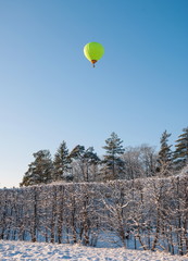 Hot air balloon in the sky over a winter snow-covered park