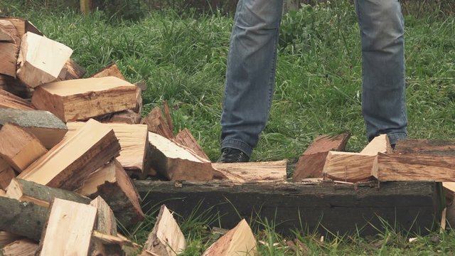 Lumberjack cutting firewood with axe in backyard