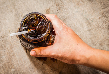 A hand holding of cola in glass with ice from top view on tabel
