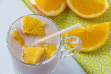 Healthy orange fruit smoothie in a glass with fresh orange slices in background, top view