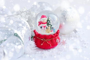 Fototapeta na wymiar A snow globe with snowman and Christmas decorations