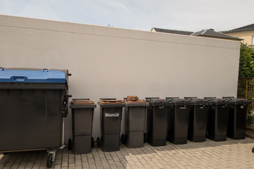 Black trash cans on the sidewalk.