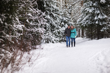 Fototapeta na wymiar Young beautiful couple walking in winter forest