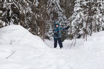 Cheerful boy walks in the winter woods