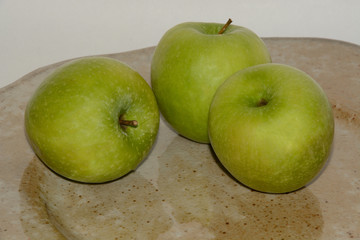 Three Granny Smith apples on hand-crafted ceramic plate