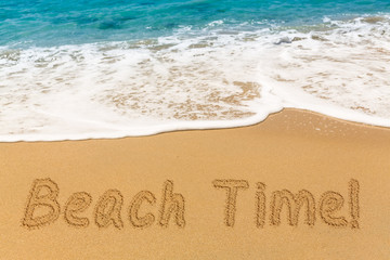 Beach Time written in sand with sea surf