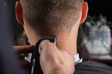 Crédence de cuisine en verre imprimé Salon de coiffure Hairdresser cutting clients hair with an electric hair clipper