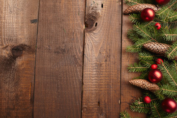 Christmas tree branch, cones, balls on the background of wood
