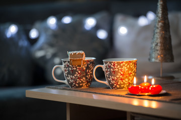 Winter scene. Living room, mugs, candle on the table.