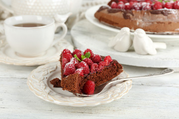 Piece of cake with chocolate Glaze and raspberries on color wooden background