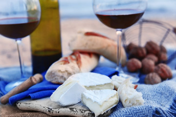 Beautiful romantic composition of red wine, bread and nuts on sandy beach