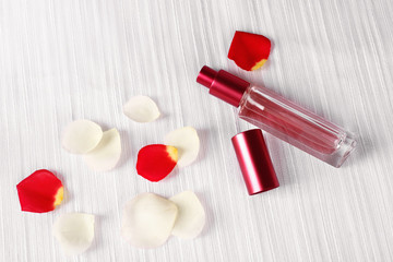 Bottle of perfume and rose petals on fabric background