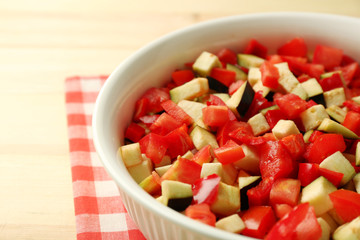 Ratatouille, stewed vegetable dish with tomatoes, zucchini, eggplant before cooking, on wooden background