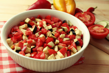 Ratatouille before cooking and ingredients, on wooden background