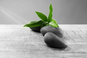 Composition of pebbles with leaf on the table against grey background