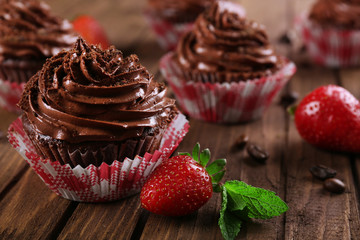 Chocolate cupcakes and strawberries on wooden background
