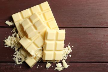 White chocolate pieces on color wooden background