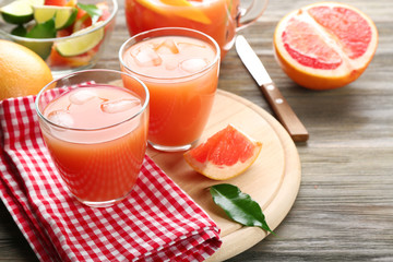Citrus juice with ice and fresh fruits on cutting board