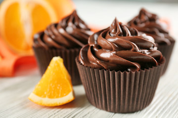 Chocolate cupcakes served with orange on table