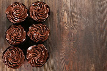Chocolate cupcakes on dark wooden background, top view