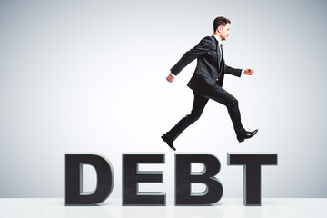 Fototapeta premium Debt burden concept with businessman running runs on debt word
