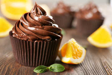 Chocolate cupcakes served with orange and mint on a table