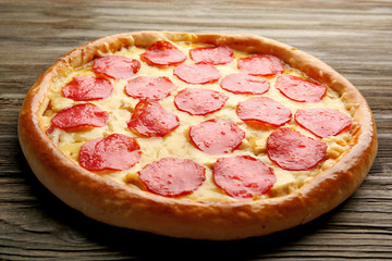 Tasty pizza with salami on wooden background