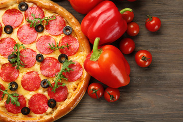 Tasty pizza with salami and red vegetables on wooden background, close up