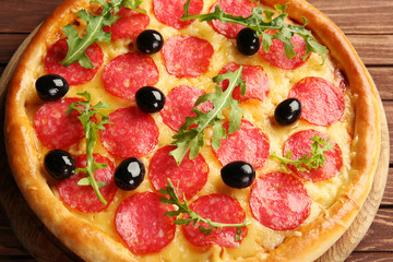 Tasty pizza with salami and olives on wooden background