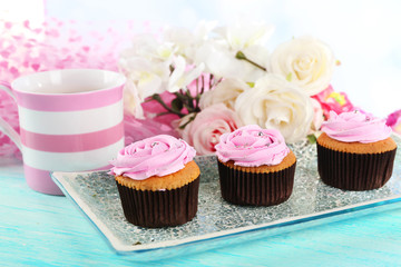 Tasty cupcakes on plate, on color wooden background