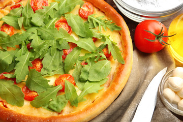 Pizza Margherita with arugula and kitchenware, close-up