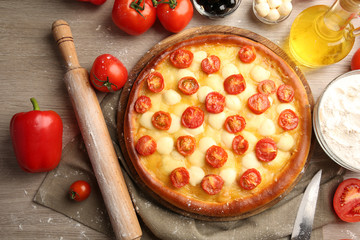 Pizza Margherita with vegetables and plunger on wooden table
