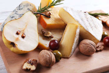 Different kinds of cheese with fruits and honey on the table, close up