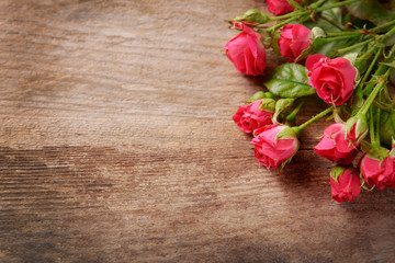 Fototapeta na wymiar Beautiful bouquet of pink little roses on wooden background, copy space