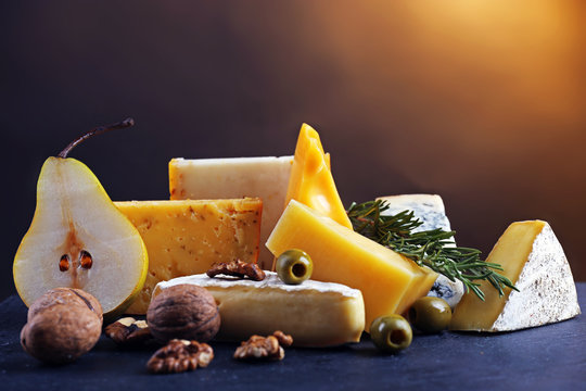 Different kinds of cheese, pear, nuts and olives, on the table, close up