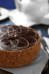 Tasty chocolate cake on color wooden background