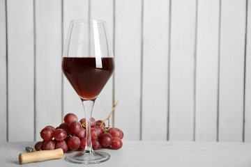 Red wine with grape on wooden wall background