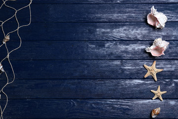 Starfish and shells in a row on blue wooden background, copy space