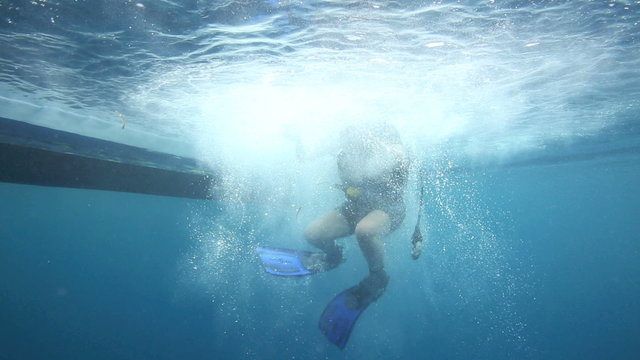 Female scuba diver backward roll entry from boat into ocean