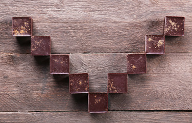 Tasty chocolate candies on wooden background. V-shaped