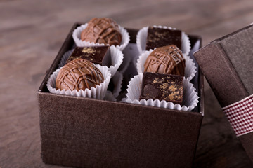 Delicious chocolate candies in beautiful gift box on wooden background