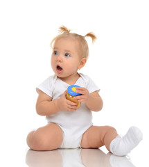 Baby girl sitting and holding jar of child mash puree food
