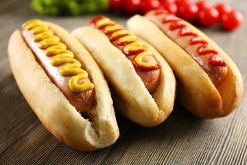Tasty hot-dogs with vegetables on wooden background