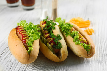 Delicious hot-dogs with chips on white wooden background, close up