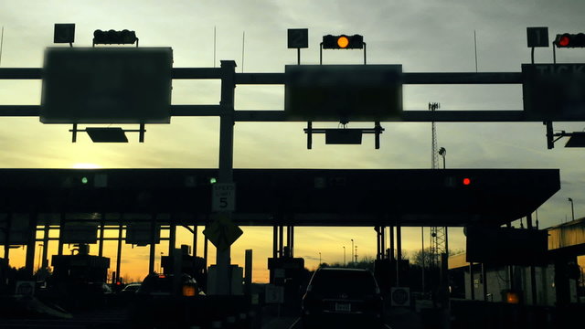 A driver's perspective of slowly passing through a turnpike's toll plaza.
