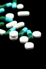 Pharmaceutical medicament, cure in container for health. Antibiotic, painkiller closeup. Medicine pills or capsules over black color background.