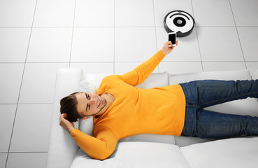 Cleaning concept - automatic robotic hoover clean the room while man relaxing, close up